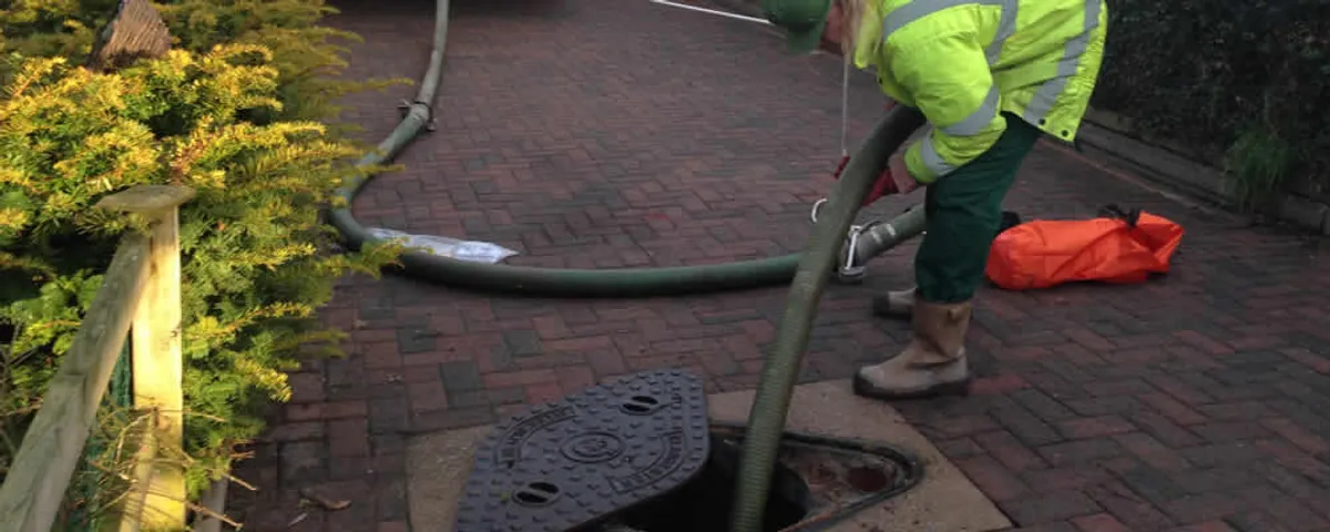Septic tank cleaning technician servicing a septic tank with a vacuum hose in Fort Collins, CO